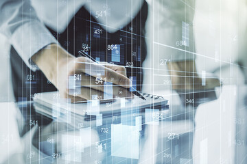 Double exposure of abstract creative statistics data hologram with man hand writing in notepad on...