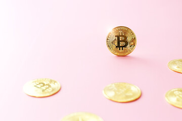 Close up golden bitcoin coin on pink background. Cryptocurrency symbol. The shiny bitcoin gold coin stands out among other coins with copy space.