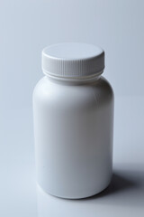 white plastic medicine jar and two white pills. light background