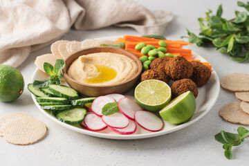 Tray served with hummus dip sauce, falafel, radish, cucumber, carrot sticks, crackers. Middle Eastern food meze appetizer plate