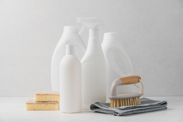White bottles with cleaning liquids, sponge rag and brush on white background. Cleaning service...