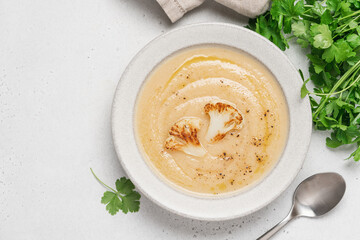 Cauliflower soup in bowl on light background. Vegetable Vegan cream soup with parsley