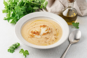 Cauliflower soup in bowl on light background. Vegetable Vegan cream soup with parsley