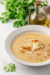 Cauliflower soup in bowl on light background. Vegetable Vegan cream soup with parsley