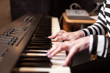 Woman playing piano record music on synthesizer using notes and laptop. Female hands musician...