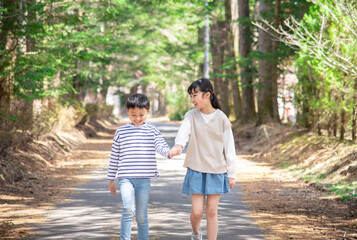Obraz premium 軽井沢の自然を手を繋いで歩くアジア人の子供