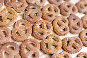 Pretzels sprinkled with sugar lie on a wooden surface