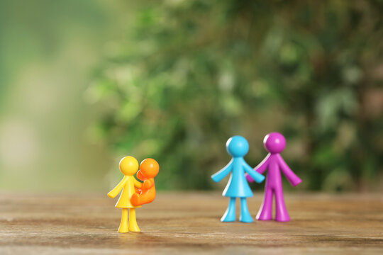 MYKOLAIV, UKRAINE - JANUARY 04, 2022: Colorful Human Figures On Wooden Table Against Blurred Green Background. Surrogacy Concept