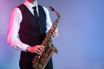 Fototapeta na wymiar Man in elegant outfit playing saxophone on color background, closeup. Space for text