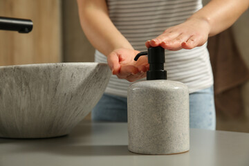 Woman washing hands with liquid soap in bathroom, closeup