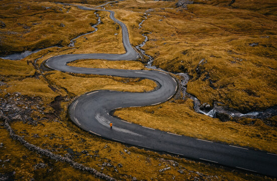 Aerial view on serpentine road on the island Streymoy near the village Nordradalur with view of Koltur island. Faroe Islands, Denmark. November 2021. Lonely wanderer on serpentine road