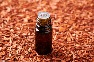 A bottle of sandalwood essential oil with pieces of red sandalwood