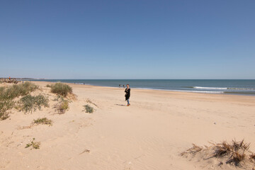 A Caucasian woman with red hair on the beach of Isla Cristina, Huelva, Spain. A blue sky and fine sand. Concept of the best beaches.