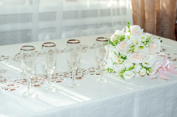 champagne glasses stand on the table next to a bouquet of flowers