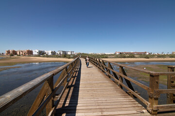 A red-haired Caucasian woman on a wooden walkway, on the beach of Isla Cristina, Huelva, Spain.