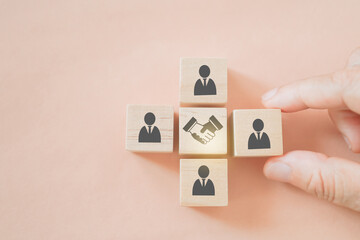 businessman's hand arrange wooden cube block with hand shake icon in middle for teamwork,...
