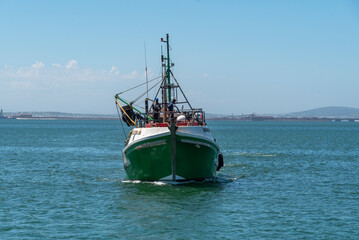 Saldanha Bay, West Coast, South Africa. 2022. Fishing boat approaching Saldanha. Two crew men tying ropes on foredeck.