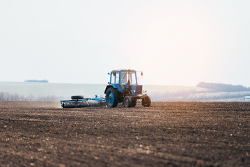 The tractor processes the field in spring. combine harvester in work on sowing wheat