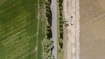 Aerial view with harvester dumping crop into a truck trailer