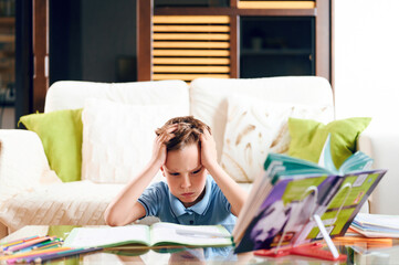 Tired and concentrated boy does homework at home. Homeschooling. Distance learning during quarantine