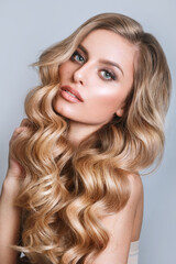 Blond woman with voluminous, shiny and curly hairstyle.Flying hair. Professional Make-up