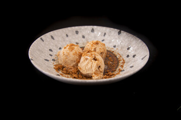 Three balls of artisan ice cream, served on a very decorative plate. Isolated on black background. Selective focus.