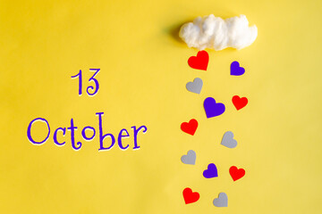 13 october day of month, colorful hearts rain from a white cotton cloud on a yellow background. Valentine's day, love and wedding concept