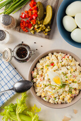 A light egg salad with celery, gherkin, pepper and mayonnaise. Served in a bowl on a light background. Top view.