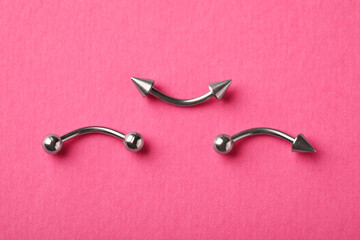 Stylish piercing jewelry on pink background, flat lay