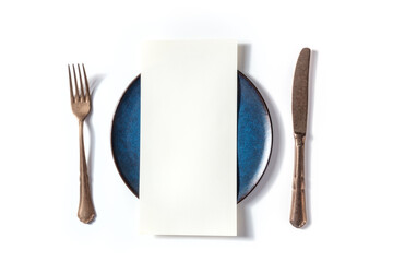 Dinner menu or invitation concept. A piece of paper on a table, with a fork, a knife, and a blue...