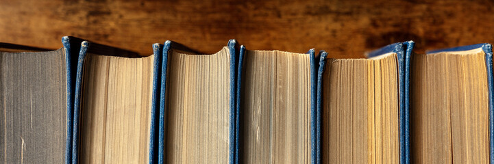 Old books on a shelf panorama. Classic literature in a second-hand bookshop. Reading novels...