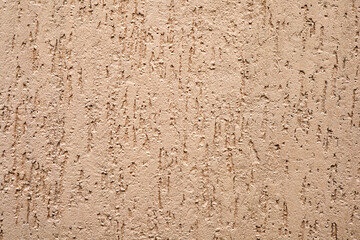 The texture of the Rough concrete wall with irregularities, painted in beige color