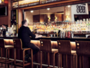 Pub interior blurry defocused background with a man sitting at the bar.