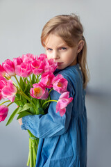 Happy adorable girl with pink fresh bouquet of tulips. Childhood,  flowers concept