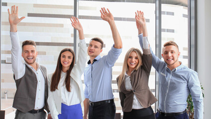 Portrait of successful business group waving hands in office