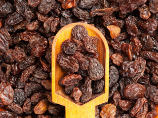Raisin in wooden scoop isolated on background from raisin. Macro. Healthy food concept