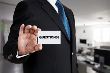 Businessman shows a business card with the word questions. Business assistance, customer support
