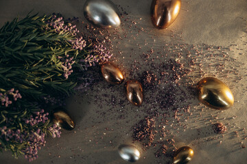 Small golden and silver eggs laying by the flowers