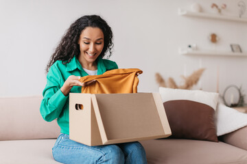 Excited Lady Customer Unpacking Received Parcel With Clothes At Home