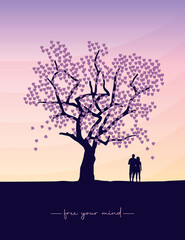 couple in love stands under a big tree at sunset