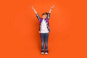 Full length photo of young cheerful boy good mood hold arms up isolated over orange color background