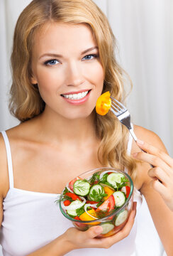 Portrait image of happy smiling woman with vegetable salad near window, indoors. Healthy eating, vegetarian, keto ketogenic diet concept.