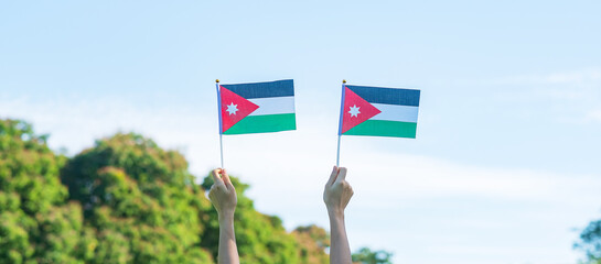 hand holding Jordan flag on nature background. Jordan Independence day and happy celebration...
