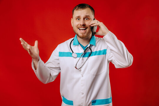 Happy Doctor Talking On The Phone On A Red Background. Portrait Of Doctor Gesturing When Talking On The Phone.