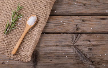 Fototapeta na wymiar Close up view of spoon of sea salt and rosemary with copy space on wooden surface