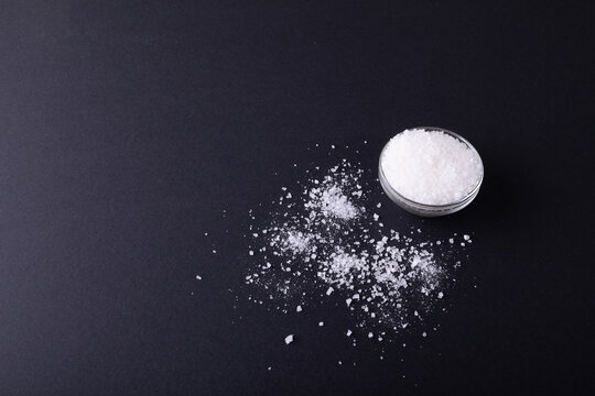 High Angle View Of Salt In Dish And Fallen On Black Table With Copy Space