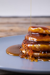 Close-up of syrup dripping on stacked pancakes in plate