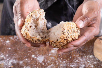 Close-up of african american male baker breaking bread on table