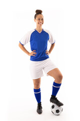 Fototapeta na wymiar Portrait of smiling biracial young female player with hand on hip and foot on soccer ball