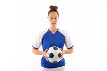 Portrait of biracial young female player holding soccer ball while standing against white background